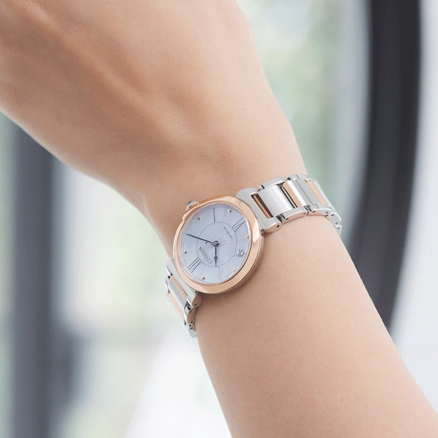 Wrist watch with a silver and rose gold band on a wrist