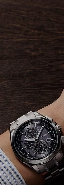 Close-up of a Citizen watch on a wrist, with a dark wooden background.