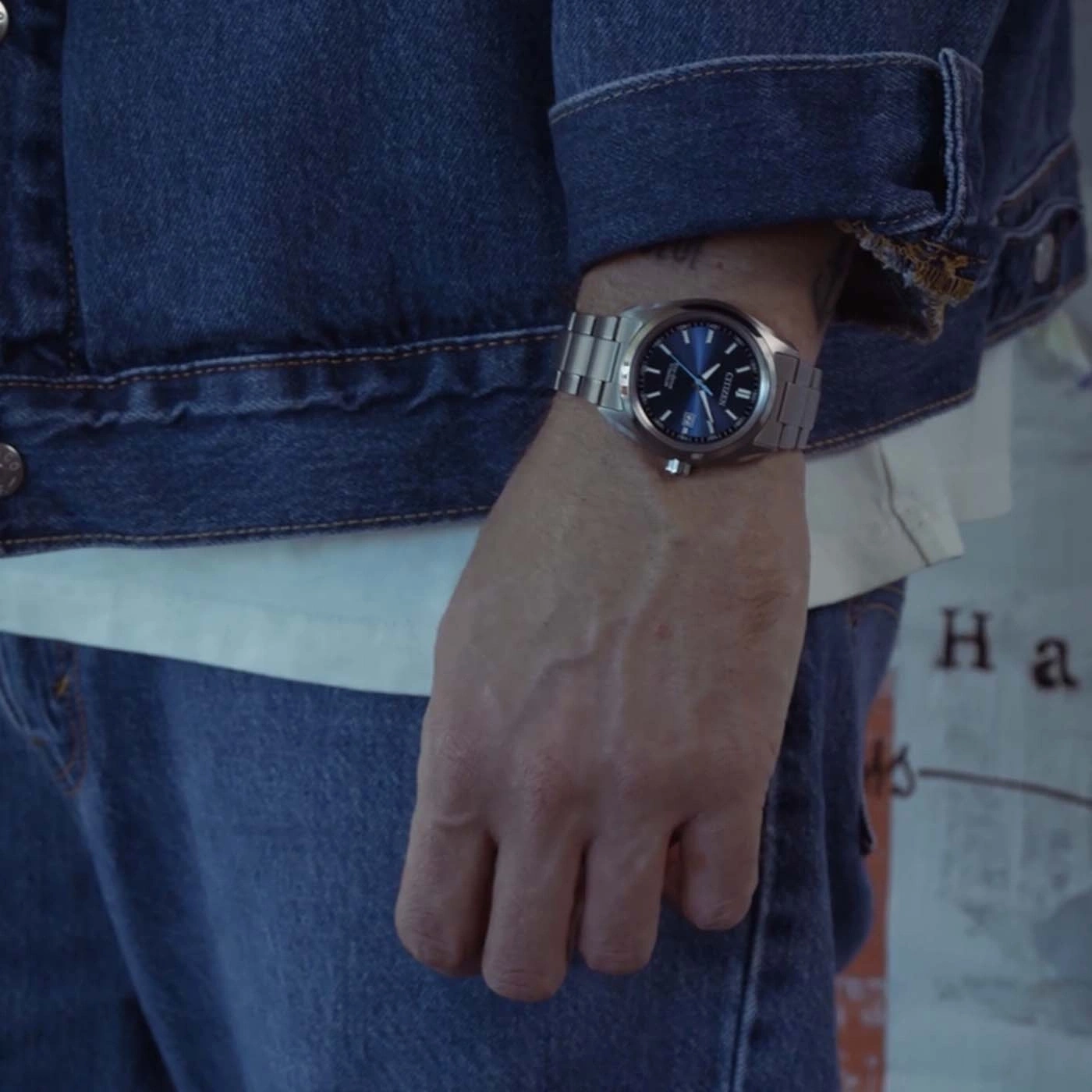 Man wearing a blue denim jacket, white t-shirt and jeans with a watch