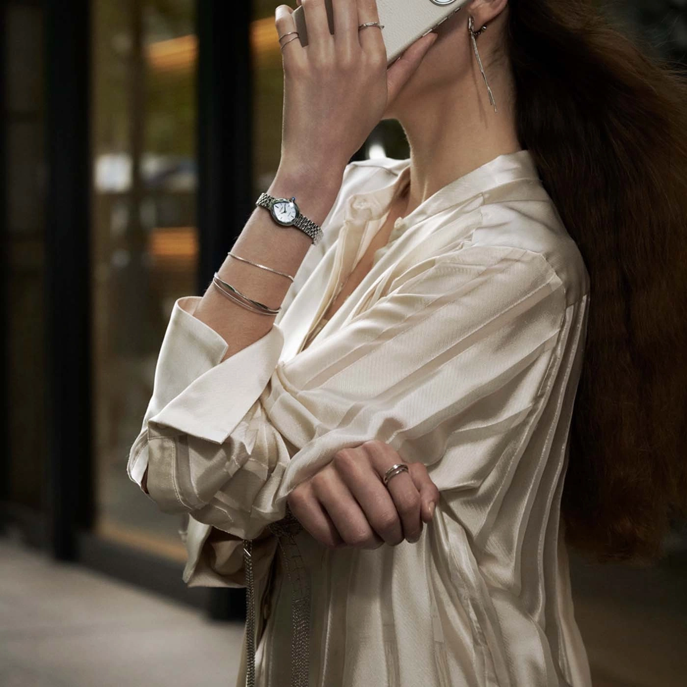 Woman wearing a watch and bracelets on her arm, holding phone