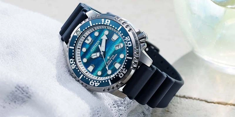 A blue Citizen Eco-Drive diver's watch with a rubber strap rests on a white towel.