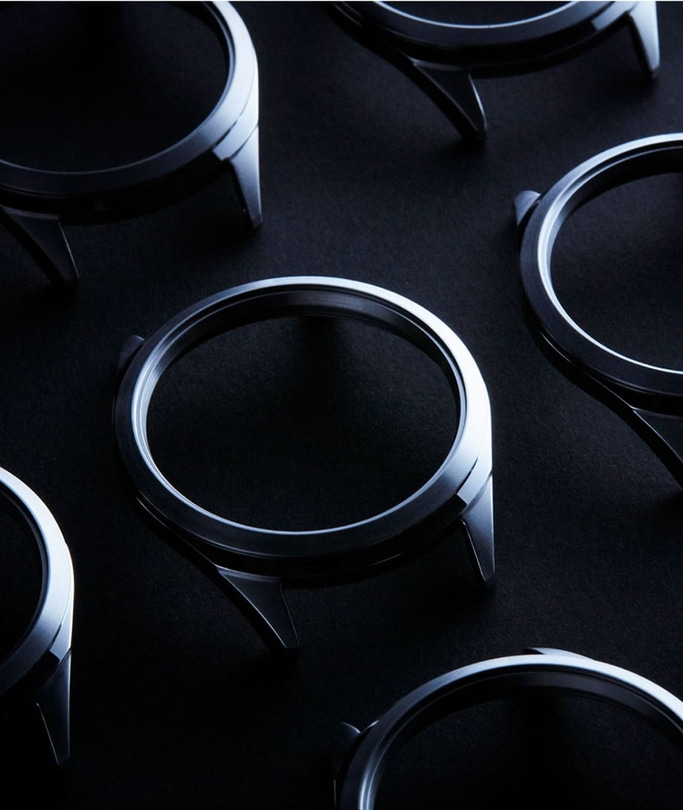 Watch cases arranged on a dark surface, metallic and shiny.