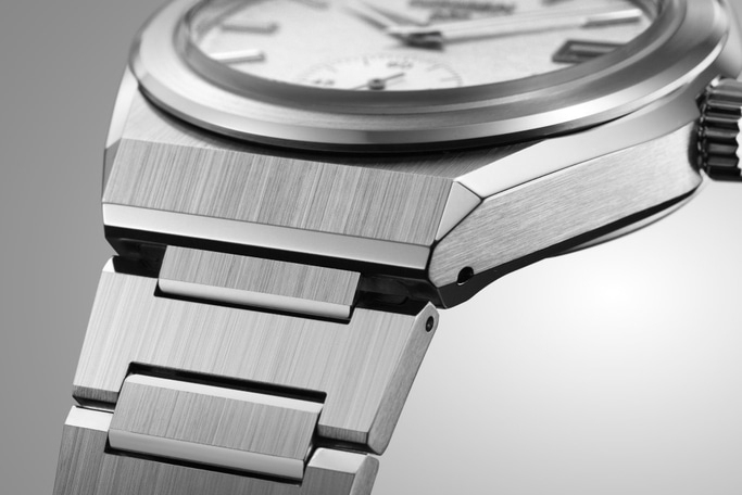 Close-up of a silver watch with a brushed metal finish and a detailed design.