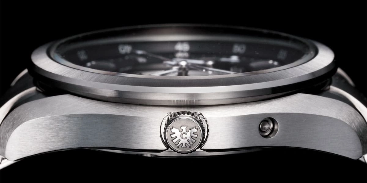 Close-up of a silver watch with a black face and intricate details.