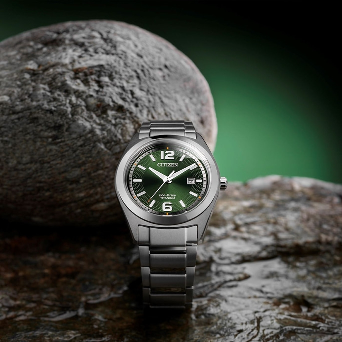 Citizen watch with green face on a rock, close-up shot.