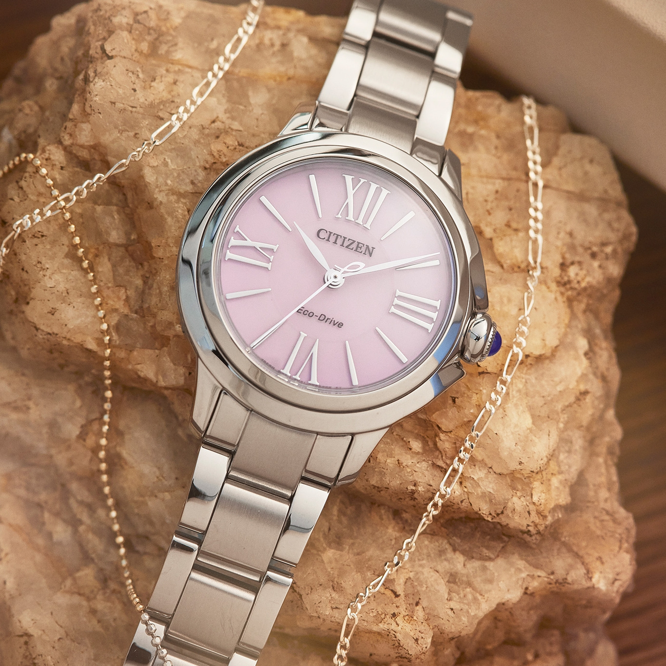 Citizen watch with pink face and silver bracelet, with jewelry.