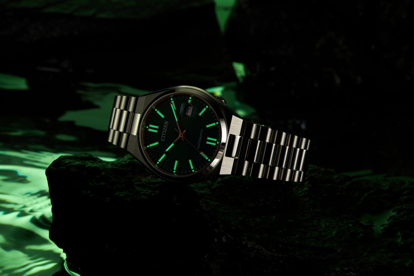 Citizen watch with glowing hands and markers on a dark background.