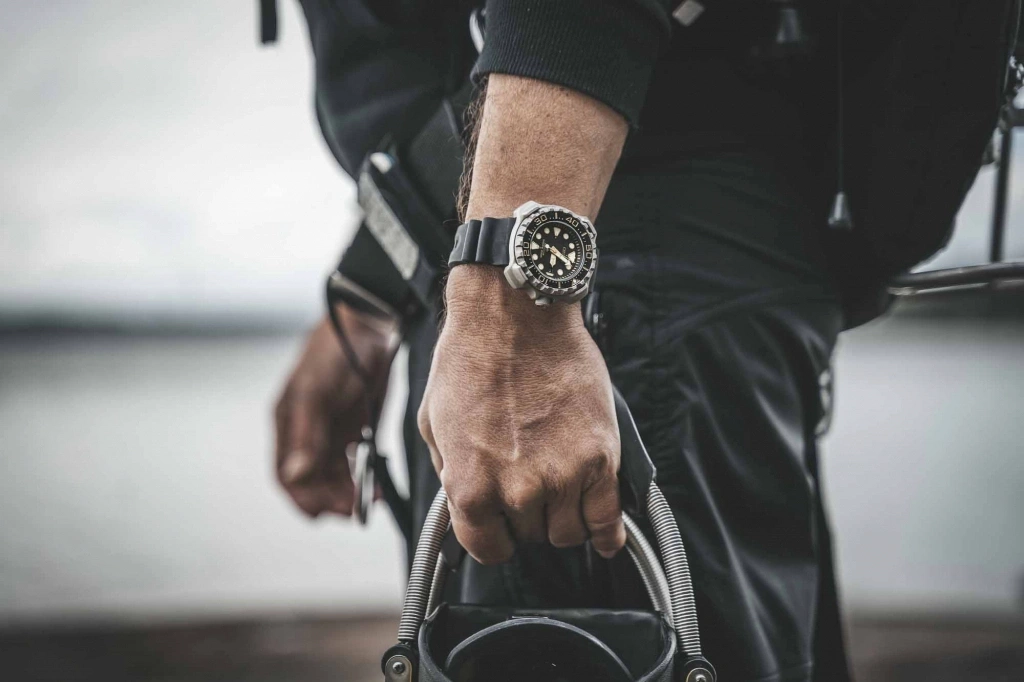 Man wearing a watch, holding equipment, close-up shot, black outfit