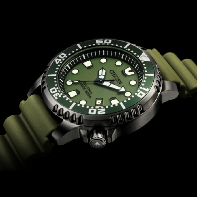 Citizen watch with green face and strap, black background, close-up shot