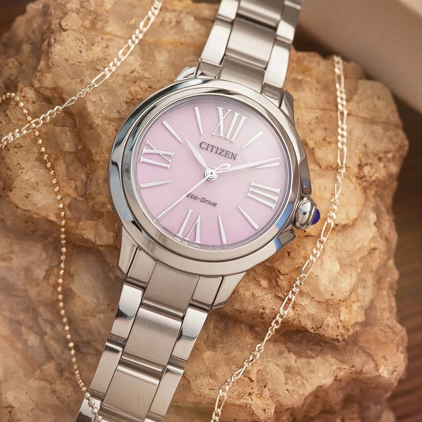 Citizen watch with pink face and silver bracelet, with a necklace.