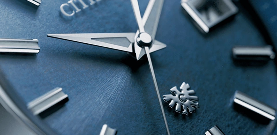 Close-up of a blue watch face with silver hands and markers, Citizen logo.