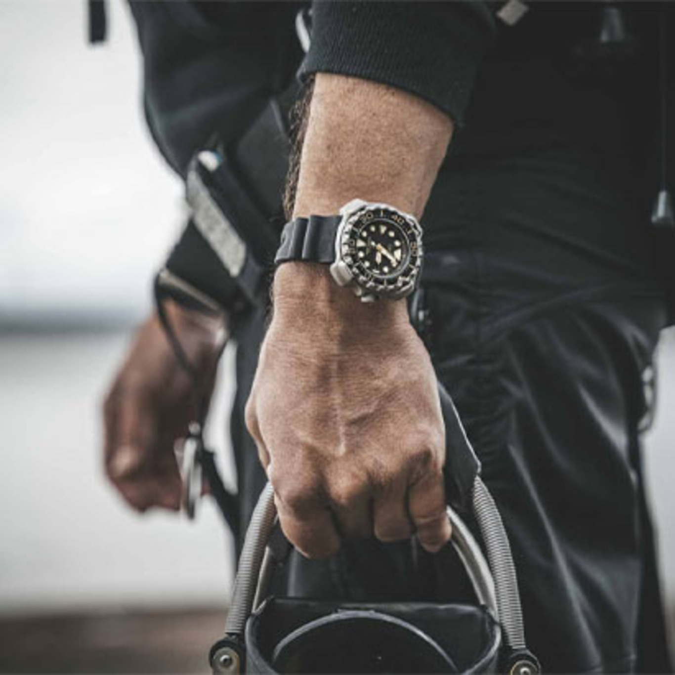 Man wearing a watch, holding equipment, close-up shot, black outfit