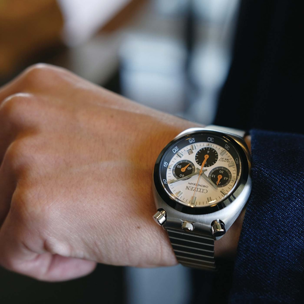 A man's wrist wearing a silver Citizen chronograph watch.