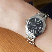 Citizen watch on wrist, black face, silver band, Roman numerals, Eco-Drive, close-up