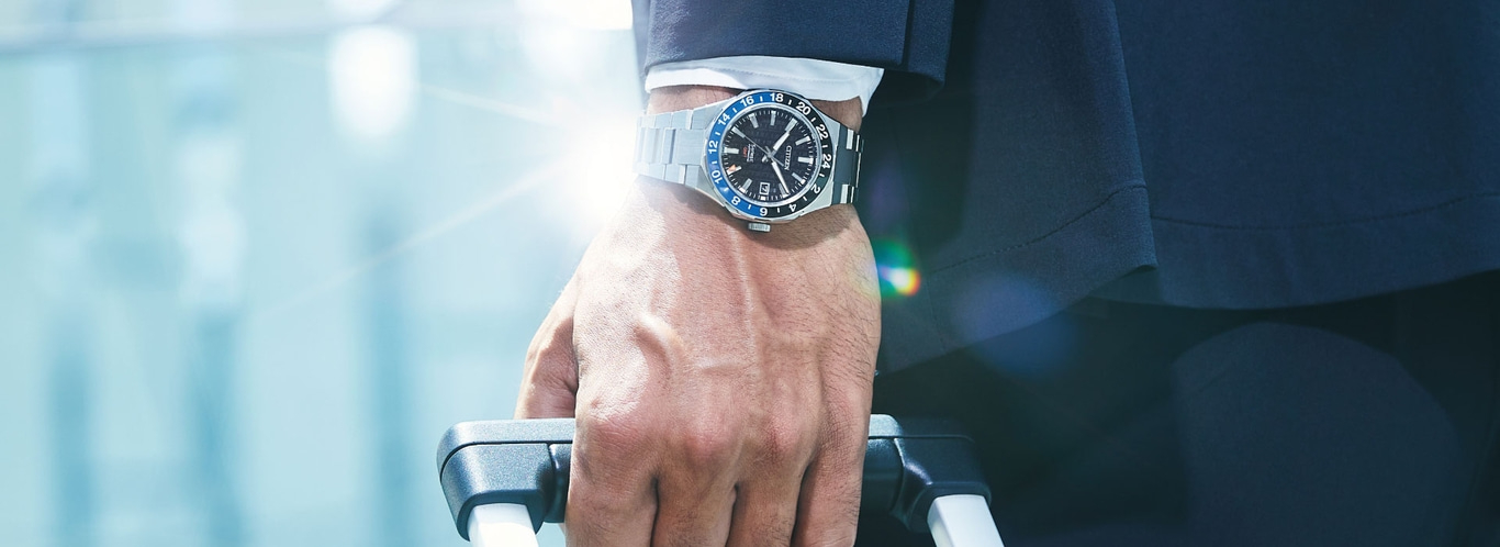 Man wearing a watch, holding a suitcase, traveling in style, business trip.