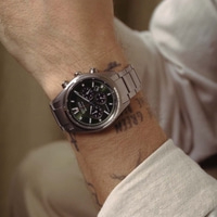 A man wears a silver Citizen Eco-Drive watch with a green dial.