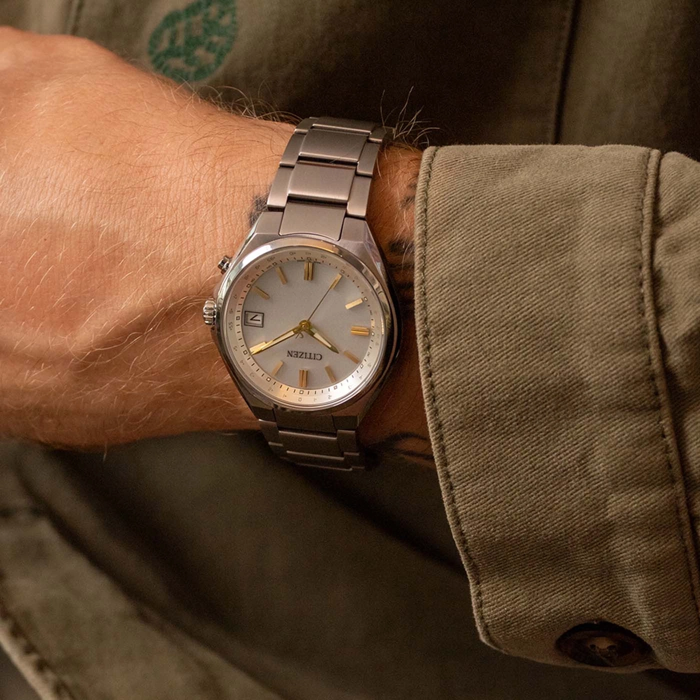 Man's watch on wrist, Citizen brand, silver band and light face.