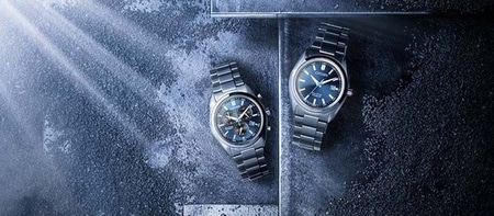 Two Citizen watches with blue dials on a textured background
