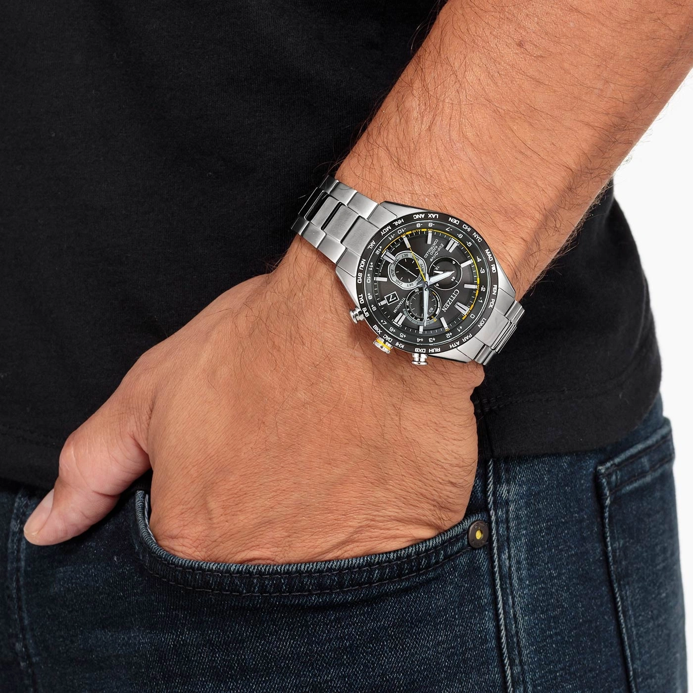 Man wearing a Citizen watch, black shirt, and blue jeans. Hand in pocket.