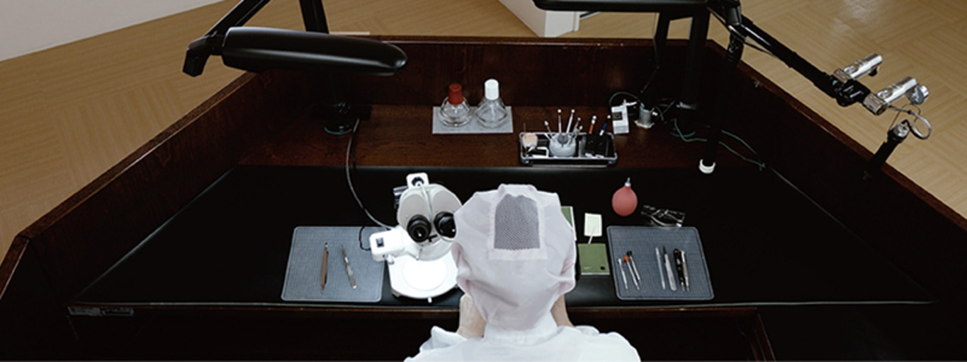 A watchmaker's workbench with a microscope and tools.