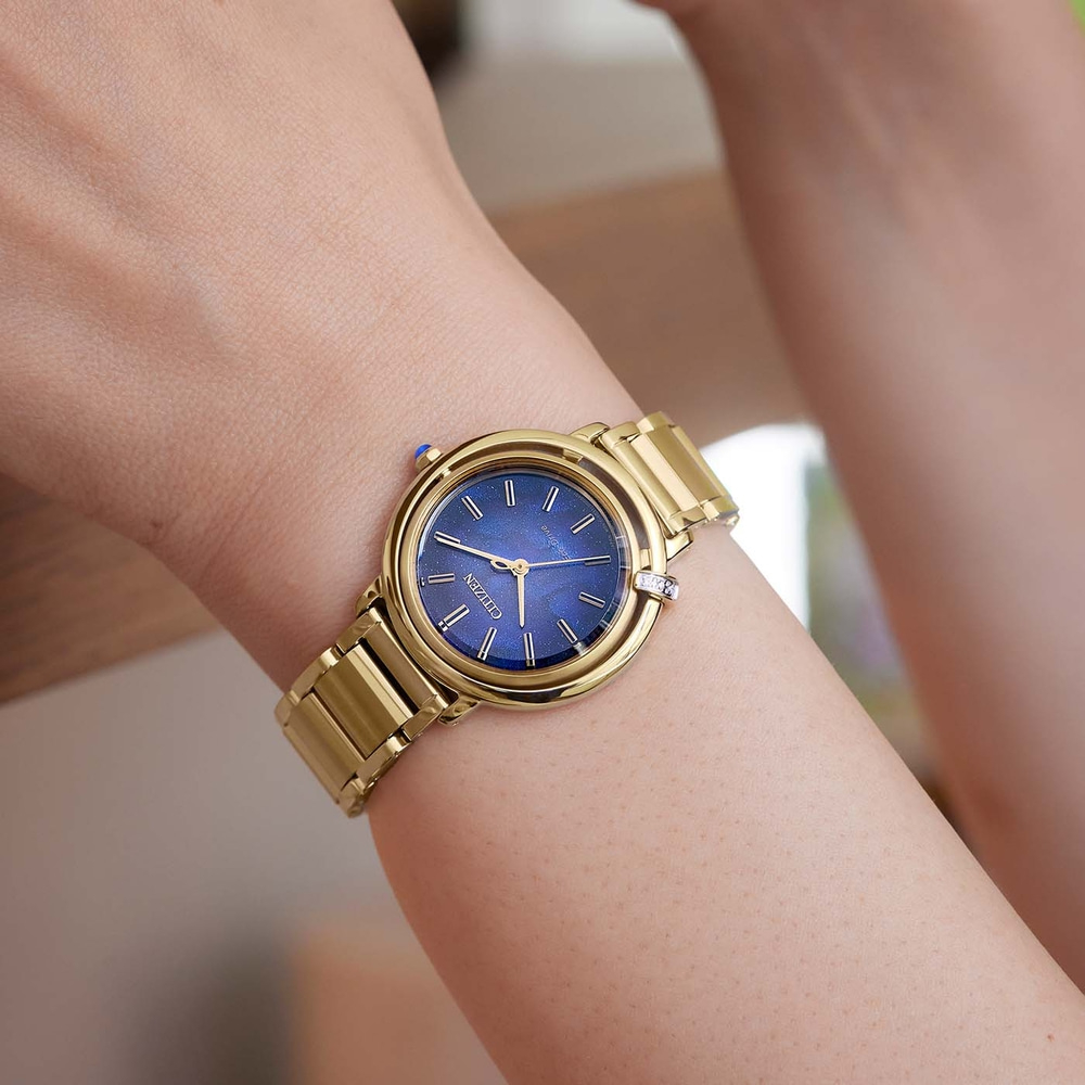 Gold watch on wrist with blue face, Citizen brand, close-up shot