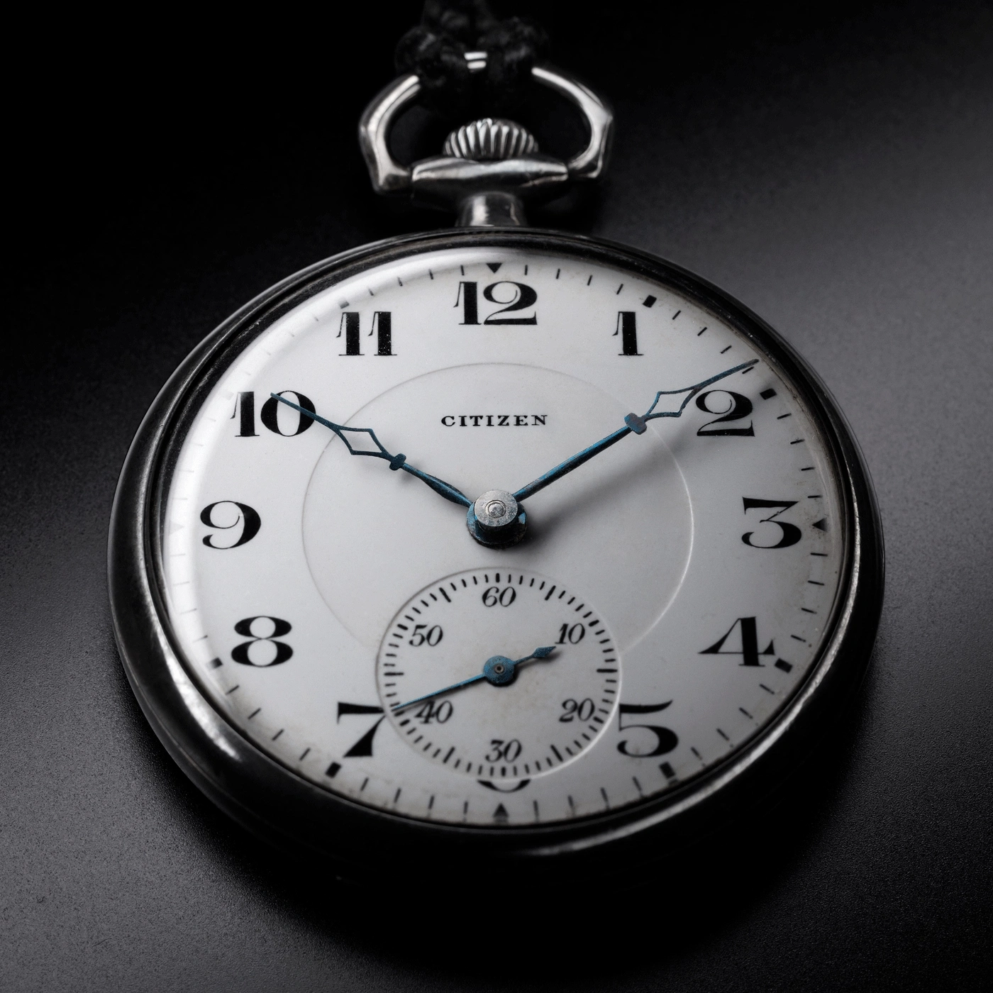 Close-up of a Citizen pocket watch, showing the time and details on a black background.