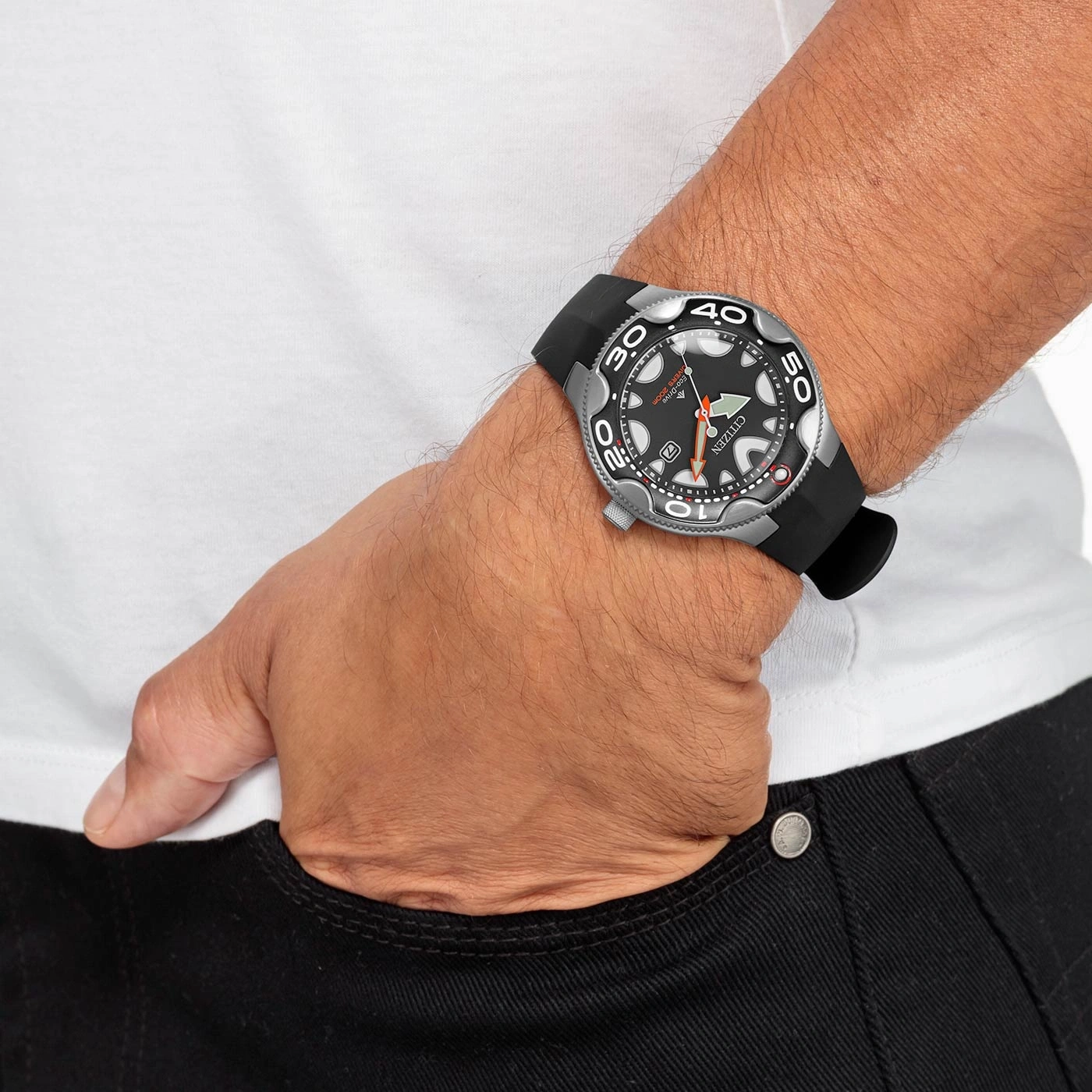 Man wearing a Citizen watch, black strap, in pocket, black jeans, white shirt.