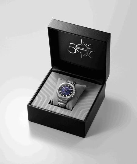 A silver Citizen Eco-Drive watch in an open black box with 50th anniversary logo.
