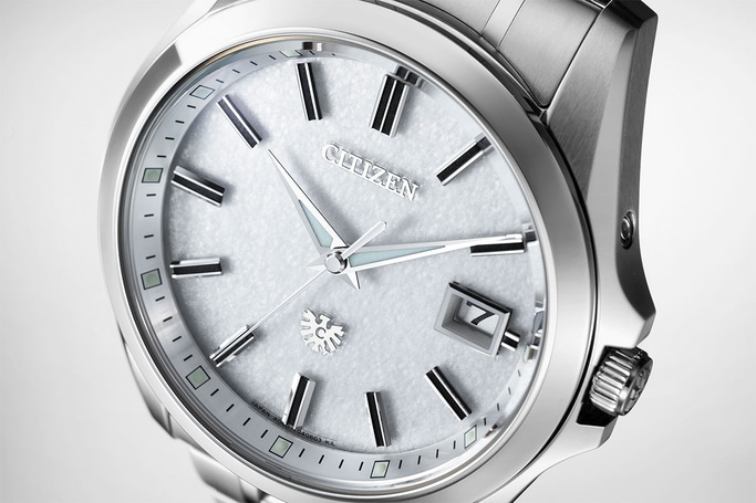 Close-up of a silver Citizen watch with a textured white face and date display.