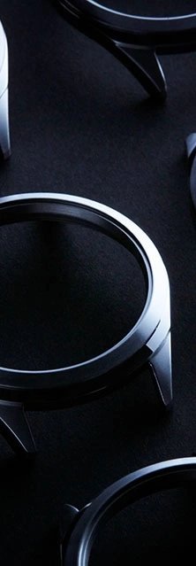 Close-up of watch cases on a dark textured surface.