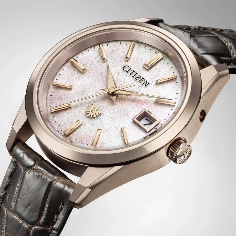 Citizen watch with a white face, gold hands, and a leather strap. Elegant design.