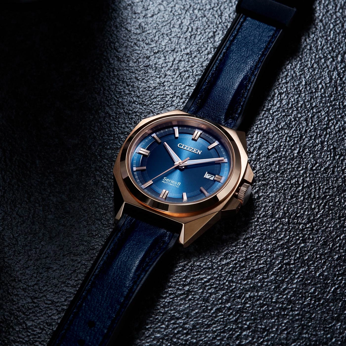 Citizen watch with blue face and leather strap on a textured surface