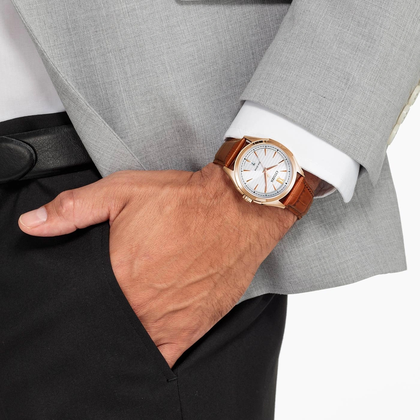 Man wearing a watch, suit, and holding his hand in his pocket.