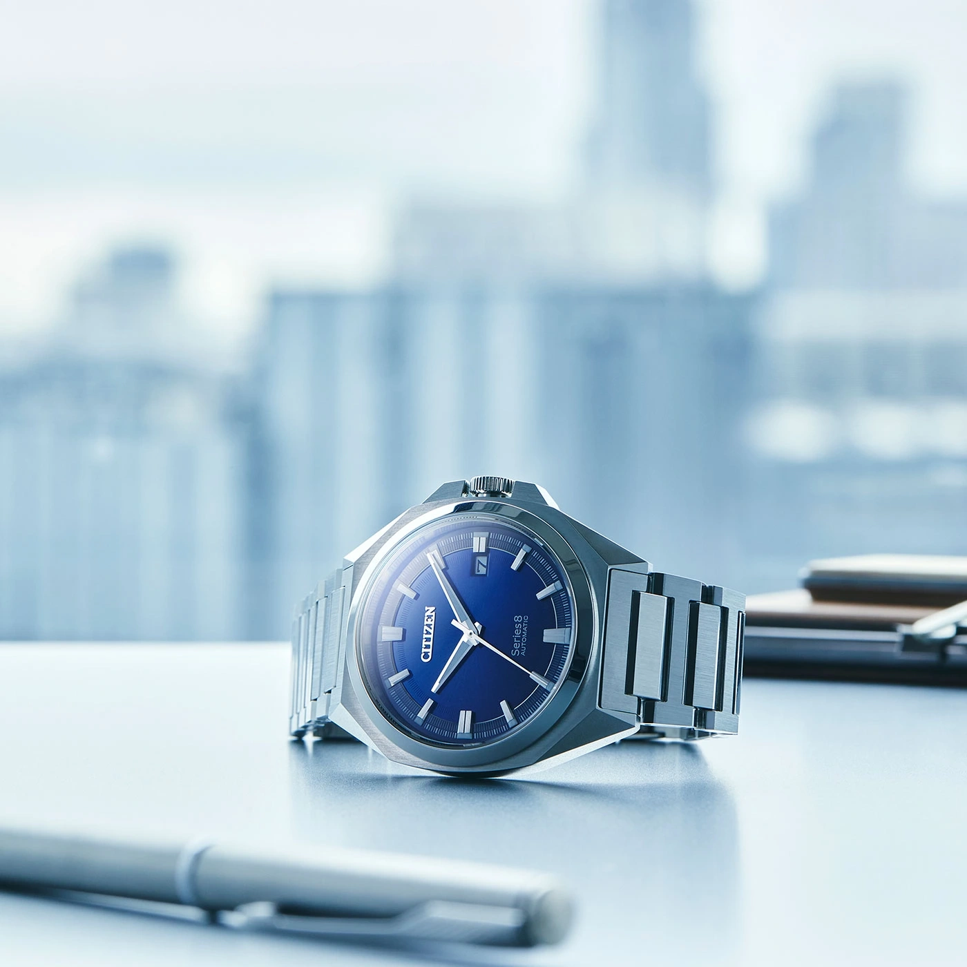 Citizen Series 8 watch with blue face on a desk with a pen.