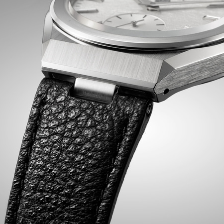 Nahaufnahme einer Luxusuhr mit schwarzem Lederarmband und silbernem Zifferblatt.