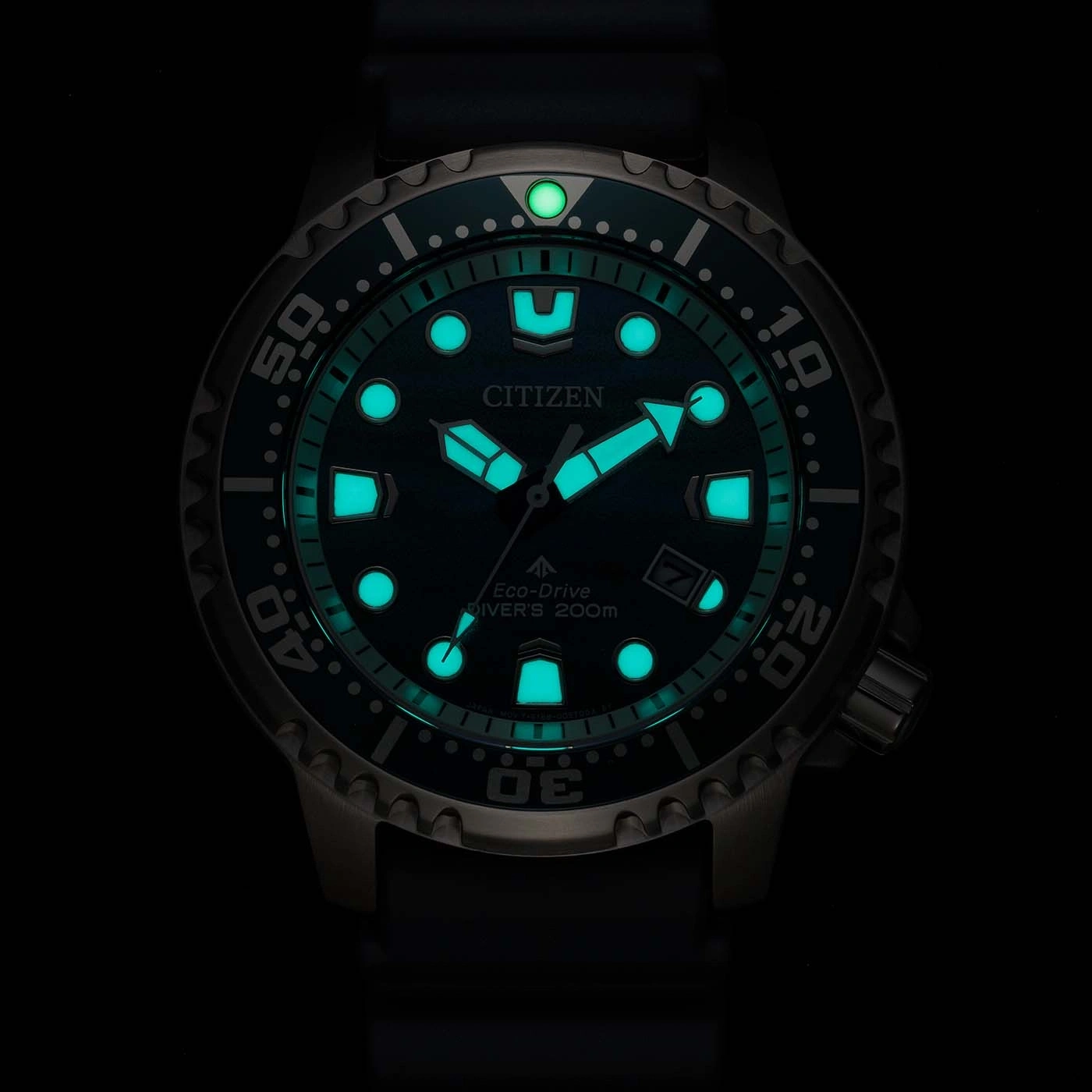 A luminous green Citizen Eco-Drive diver's watch glows in the dark.